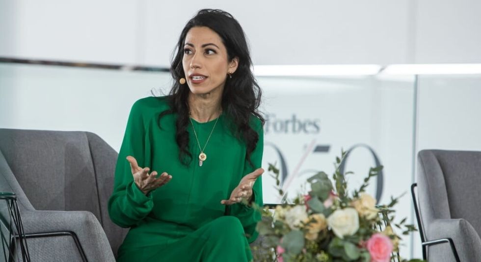Huma Abedin in green dress talking during Forbes interview