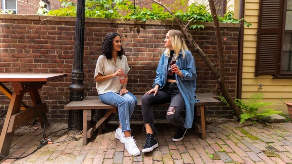 two women speak on a bench