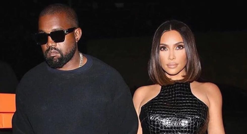 Kim Kardashian și Kanye West îmbrăcați în negru și ținându-se de mână
