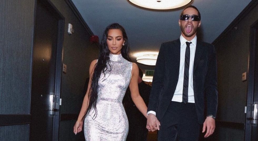 Kim Kardashian and Pete Davidson walking down a hallway holding hands