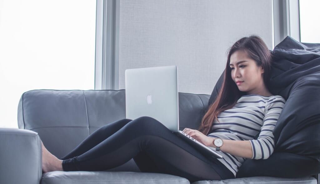 woman looks at computer at couch
