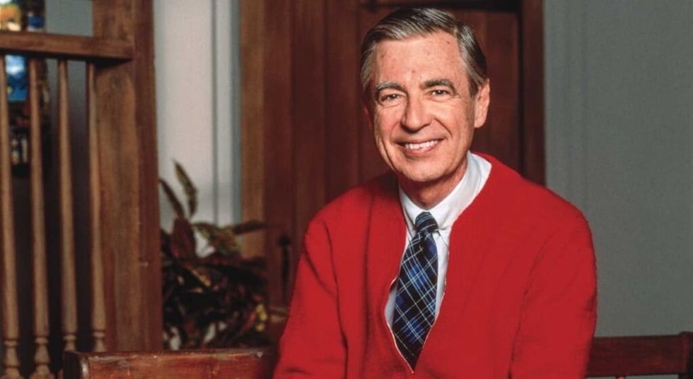 Domnul Rogers zâmbind pentru cameră într-o jachetă roșie