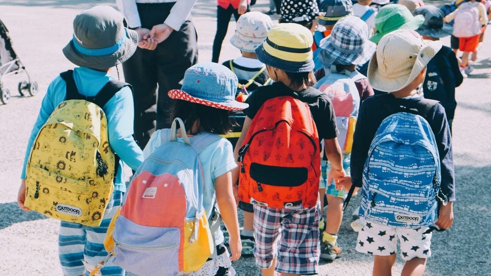 children wearing hats and backpacks and walking