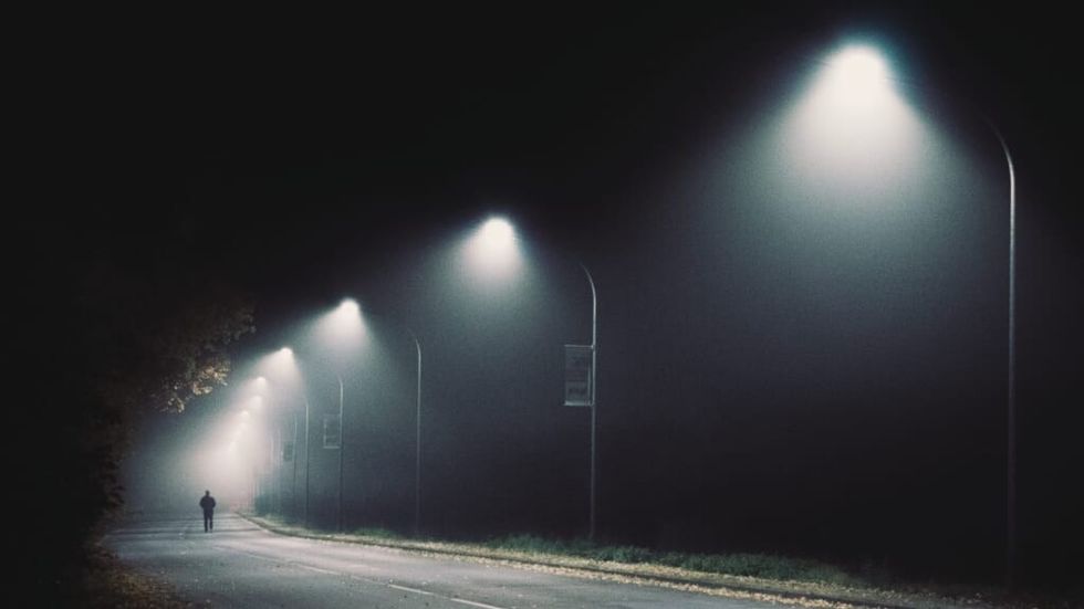 streetlights on a dark street, mysterious figure