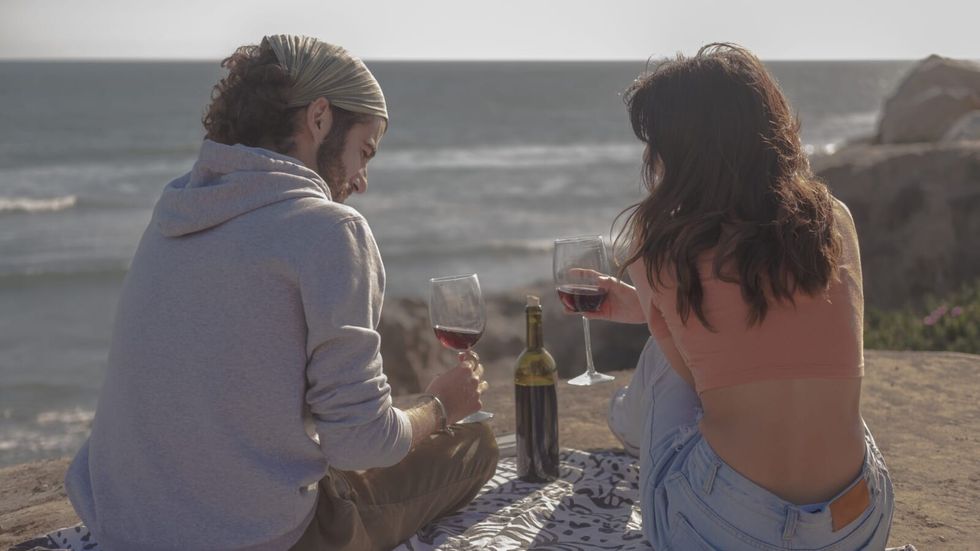 Un bărbat și o femeie beau vin pe plajă