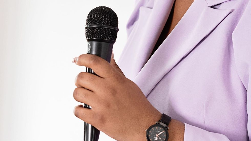 woman in a lavender outfit holding a black mic