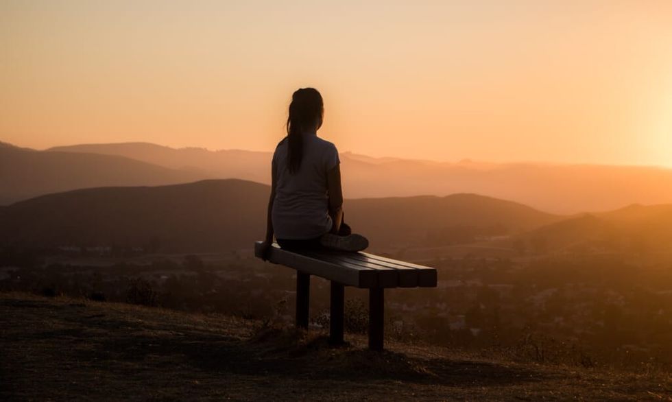 woman reflects at sunset atop a mountain