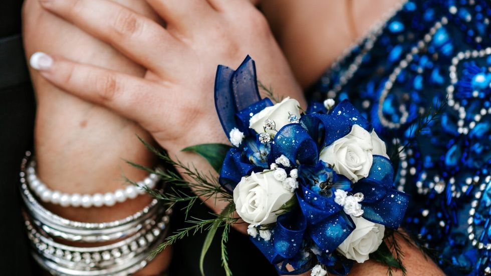 woman wearing pearl and silver bangles on one hand and a blue and white corsage on the other