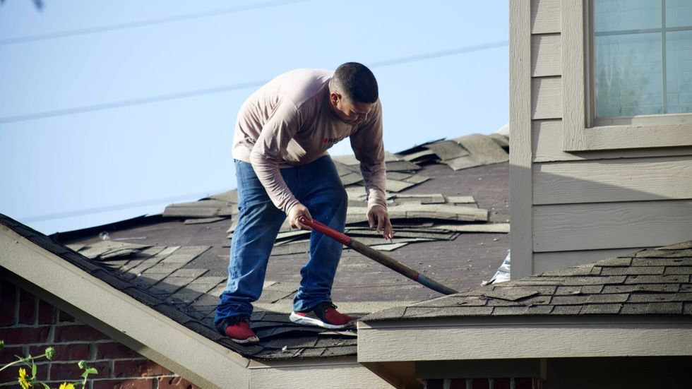 man fixing a roof of a house