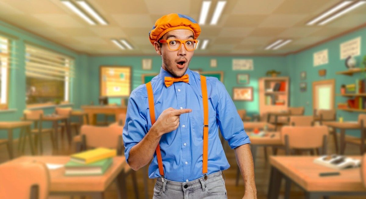Clayton Grimm as Blippi with blue shirt and orange suspenders standing in front of a classroom.