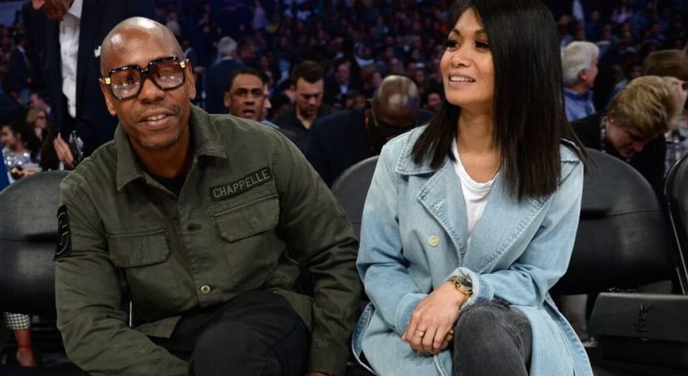 Dave Chappelle in green jacket sitting next to wife Elaine in a blue jacket.