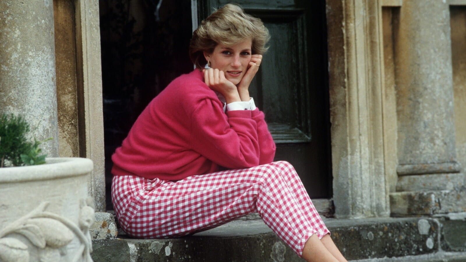 woman sitting on the steps wearing a pink sweater and pink and white pants