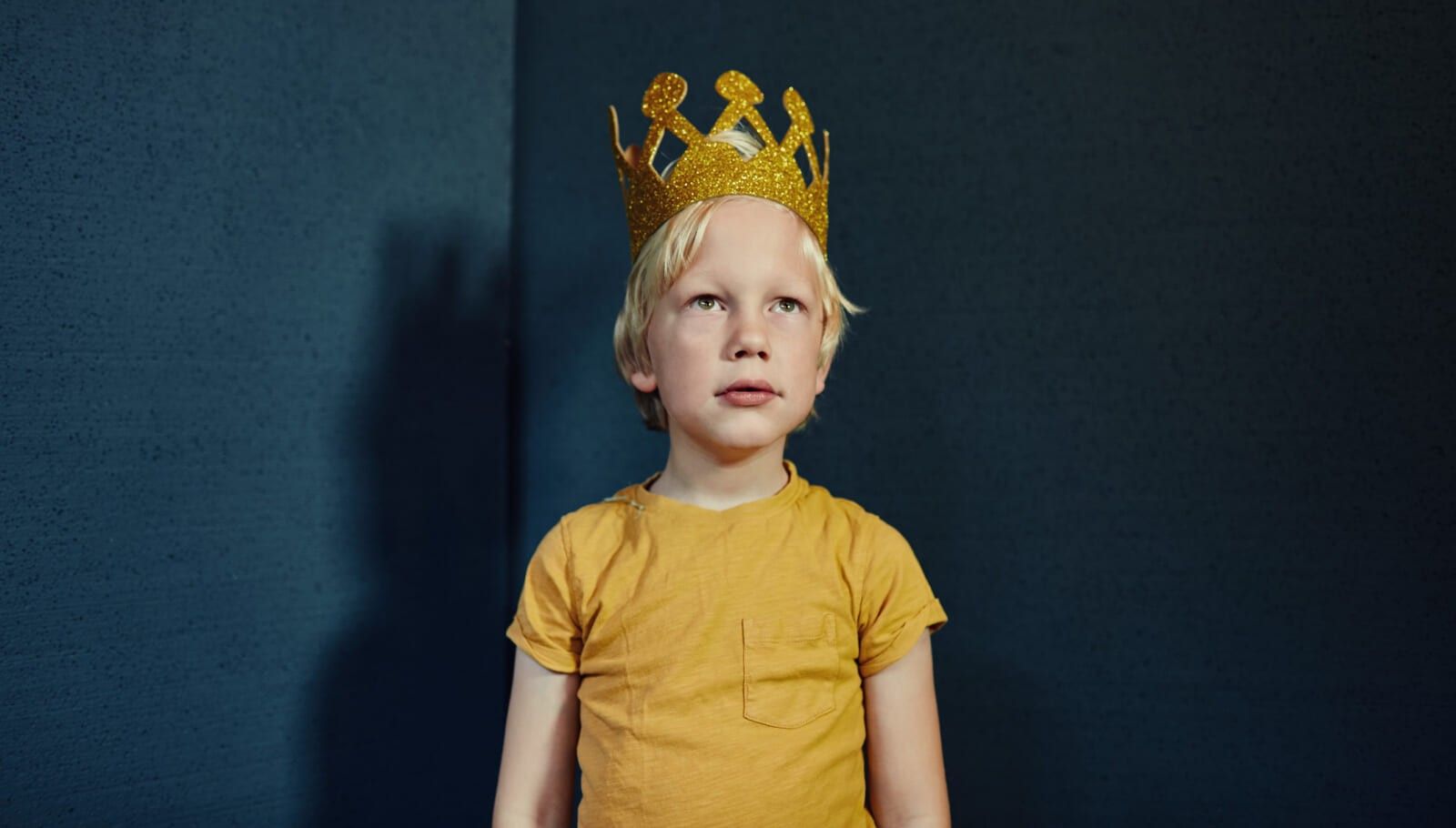 Portrait of a young boy wearing a gold crown party hat