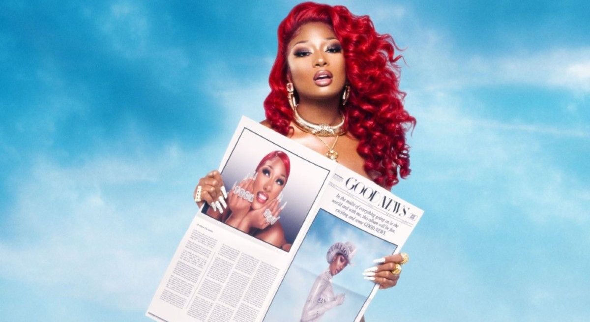 Megan Thee Stallion with red hair holding a newspaper.
