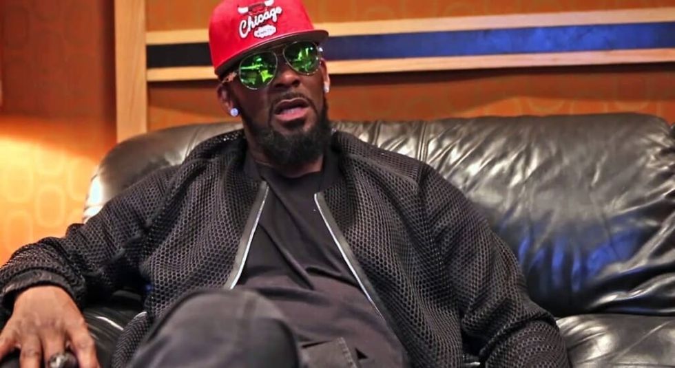 R. Kelly in a black jacket and red Chicago Bulls during an interview.