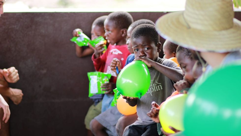 children blowing green balloons 