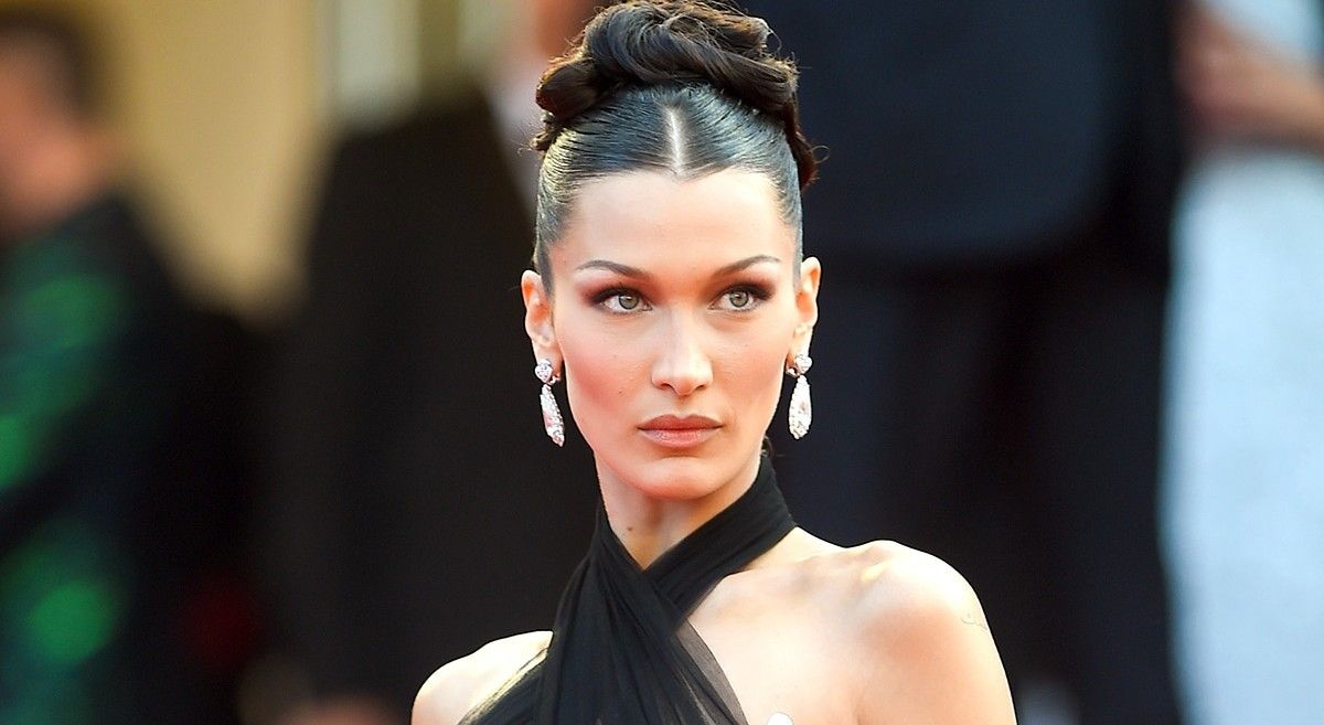 Bella Hadid on red carpet in black dress with hair pulled back.