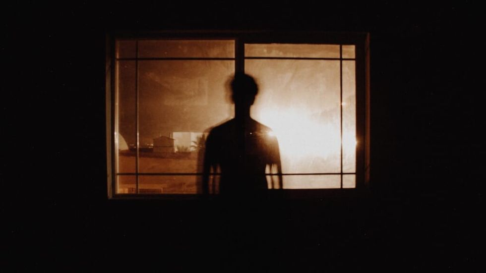 man's dark silhouette in a room window