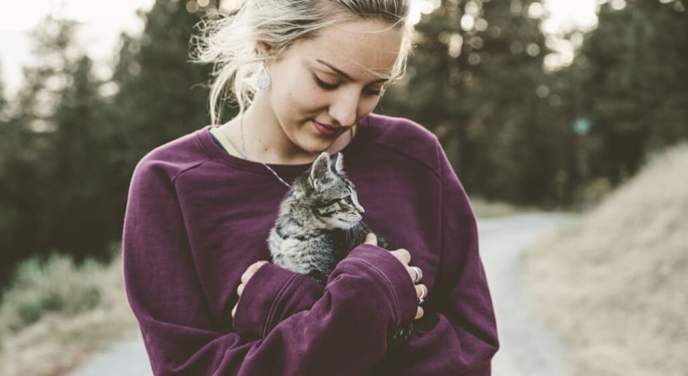 woman holds pet cat outside