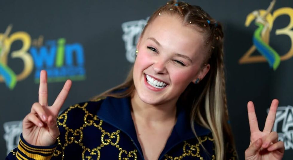 JoJo Siwa giving the peace sign and smiling