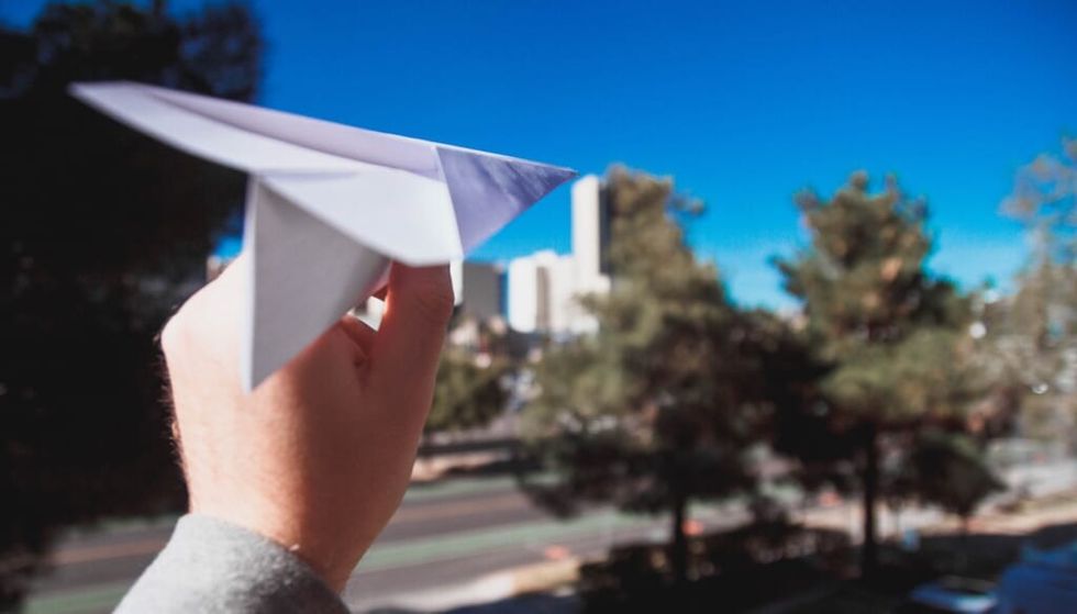 paper airplane being thrown outdoors