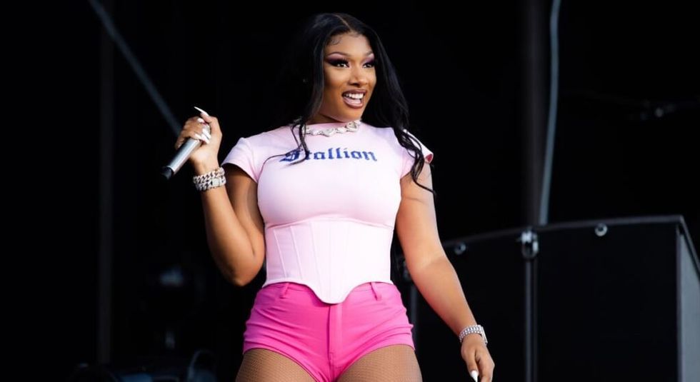 Megan Thee Stallion on stage in pink shorts and white top.