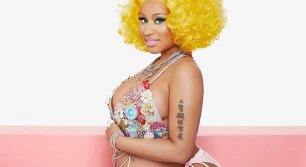 Nicki Minaj in jeweled top, holding her pregnant stomach.