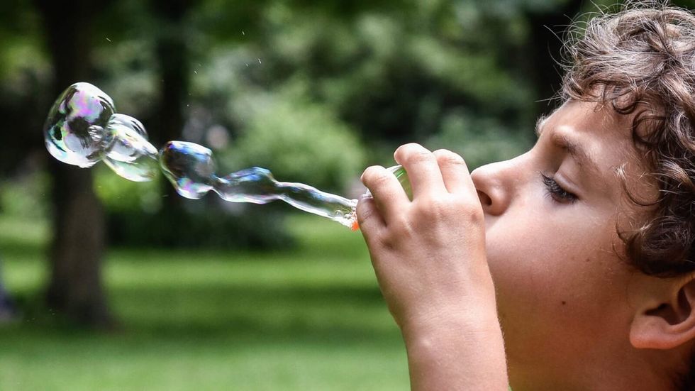 side view of boy blowing bubbles