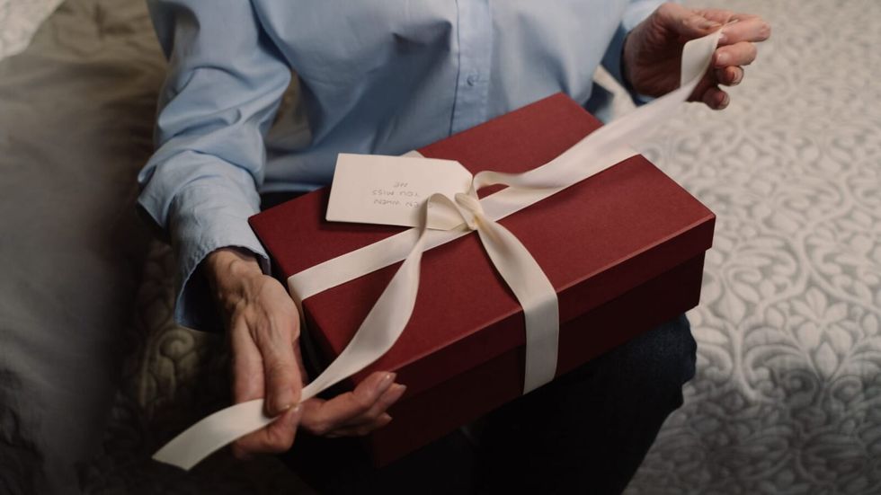 person opening a red gift with white ribbon