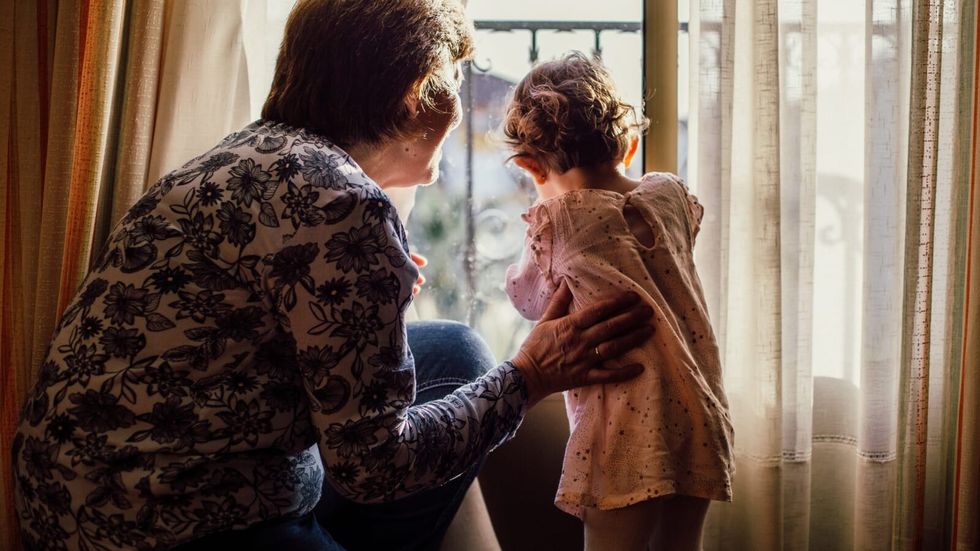 elderly woman with little girl looking out of the window