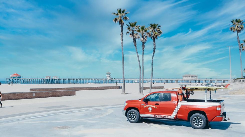 red truck parked in an empty lot with palm trees in the background