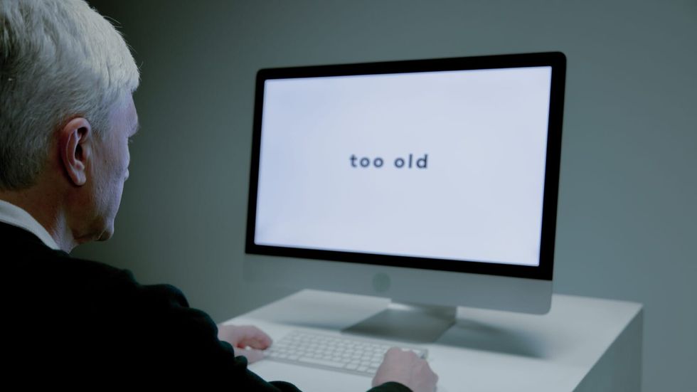 elderly man sitting in front of a computer with "too old" on it