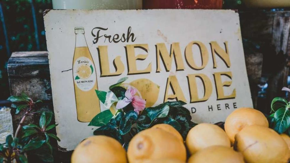 a sign talking about fresh lemonade with lemons placed in front of it