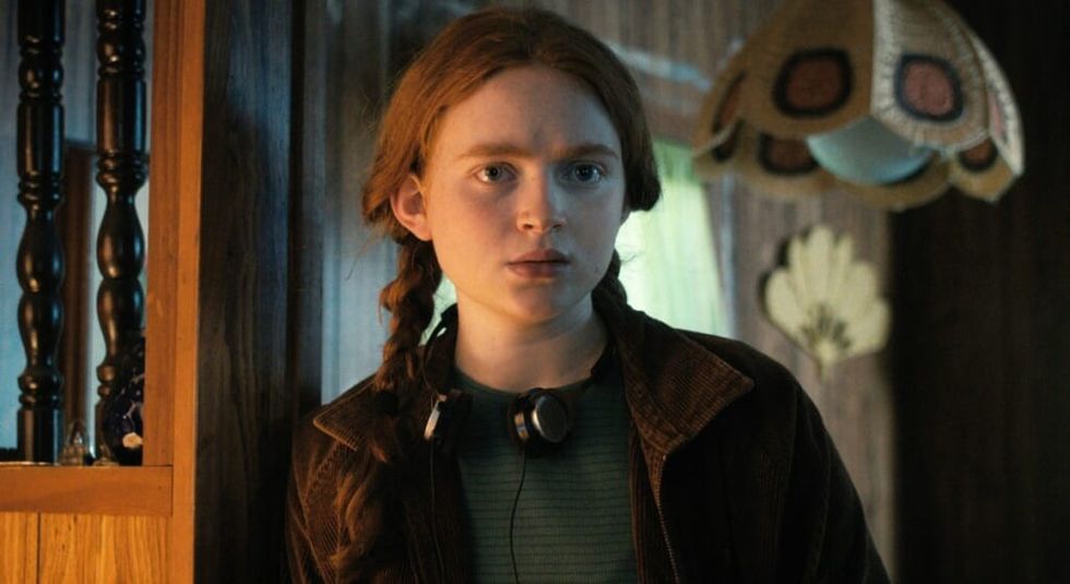 Stranger Things star, Max, stands with her headphones around her neck.