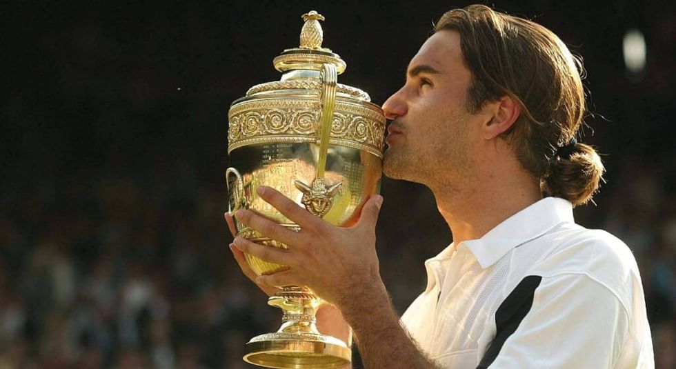 Roger Federer kissing his Wimbledon trophy.