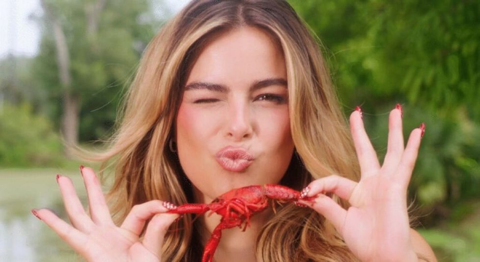 Addison Rae holding a crawfish and blowing a kiss.