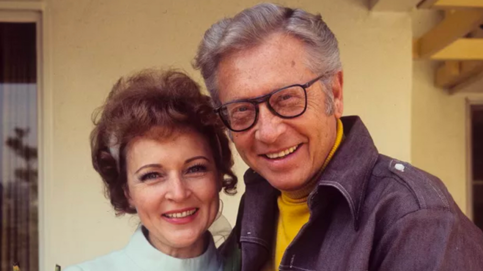 A young Betty White and her husband Allen Ludden smile at the camera.