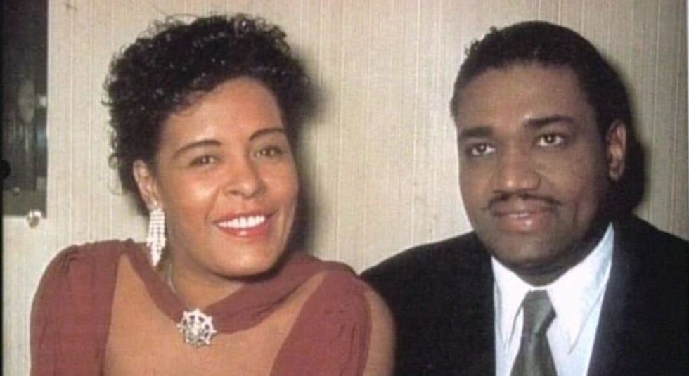 Billie Holiday in red dress sitting beside husband Louis Mckay.
