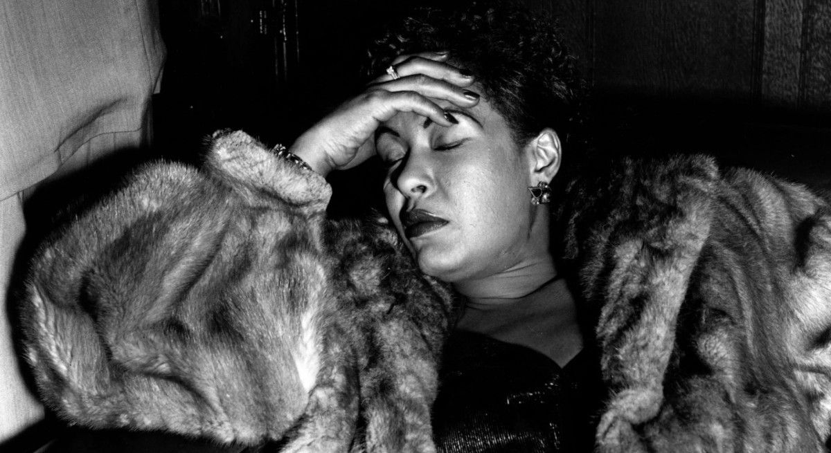 Billy Holiday in fur coat sleeping on a couch.