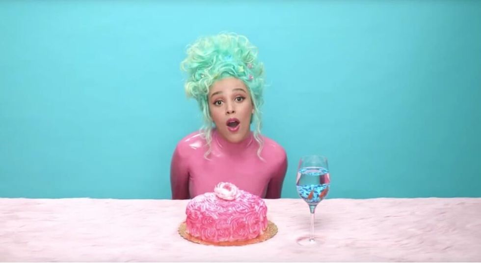 Doja Cat music video wearing pink latex suit and green hair in front of a cake.