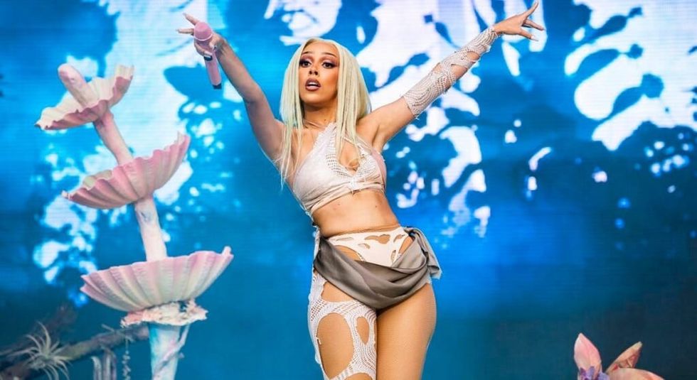 Doja Cat with long white hair and white outfit during a live performance.