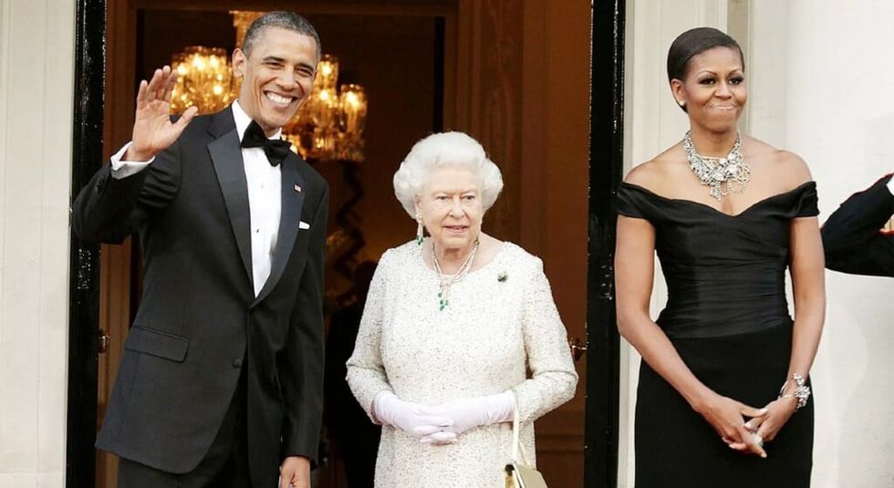 Queen Elizabeth in white dress posing with Barack and Michelle Obama.