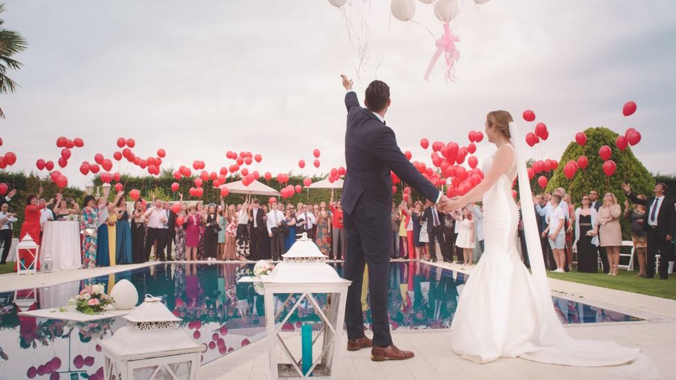 a couple getting married with red balloons in the air