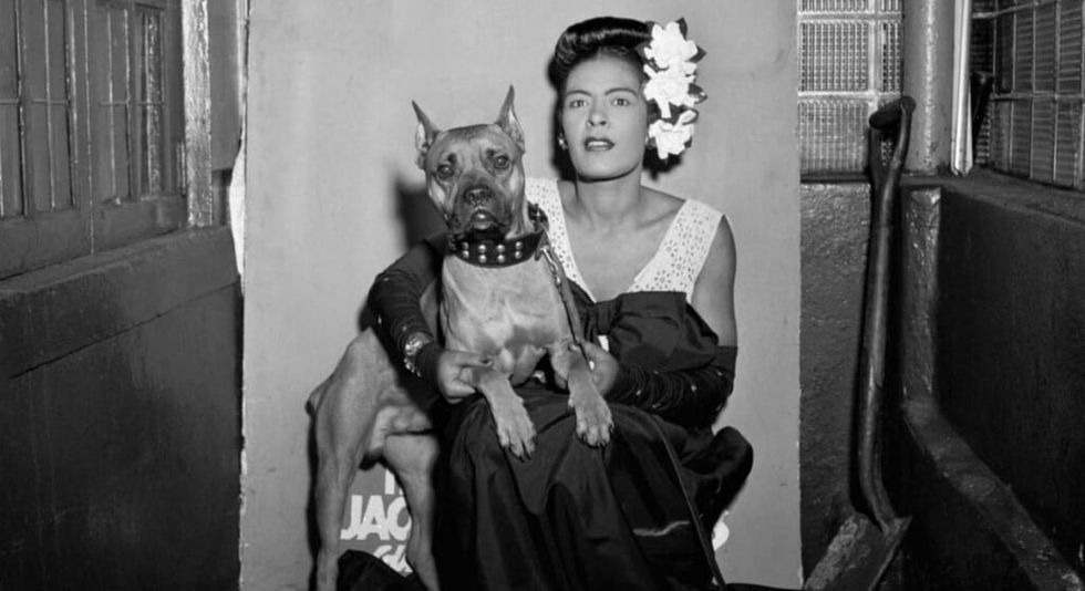 Billie Holiday in a stable with her dog.