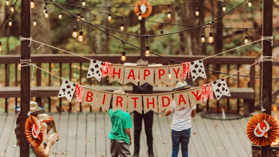 "happy birthday" sign hung outside with lights around