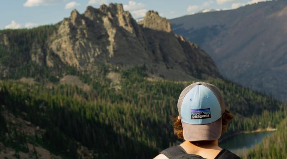 man in a brown and blue cap looking at mountains