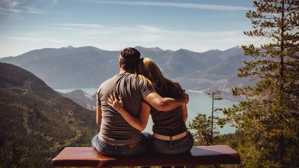 Couple sitting on a bench overlooking the mountains