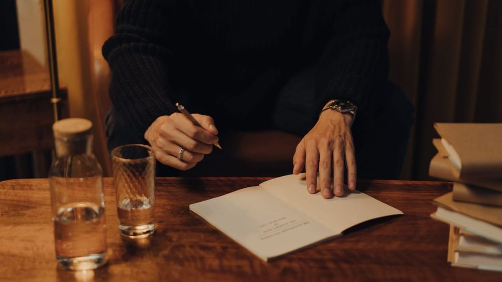 person wearing long sleeve black shirt writing on a white paper