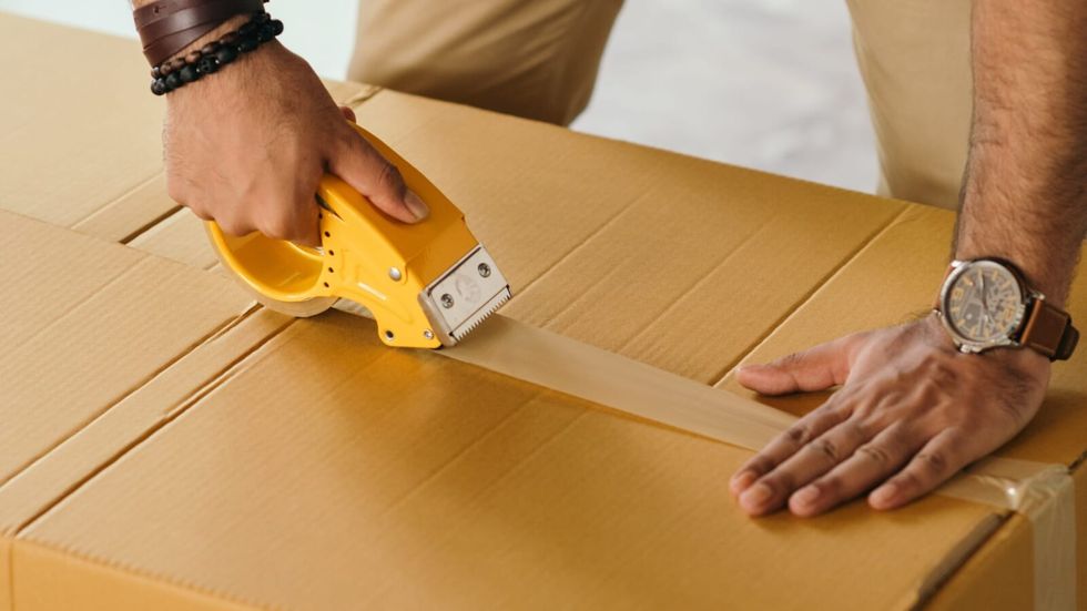 person sealing a box with tape