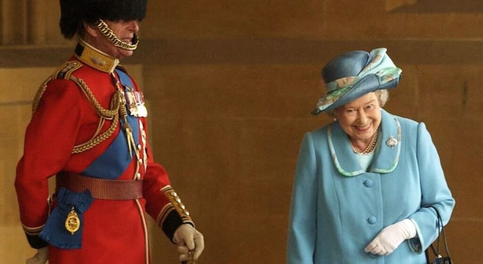 Queen Elizabeth in blue suit caught giggling with husband Prince Philip.